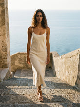 Load image into Gallery viewer, THE TARA handcrafted leather strappy sandal in cream on model  stone steps water backdrop — LUXUL COLLECTIVE